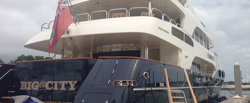Large white motor yacht Big City with a Cayman Islands flag moored at a dock.