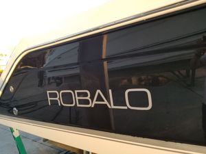 Close-up of a dark boat hull with white ROBALO lettering on the side.