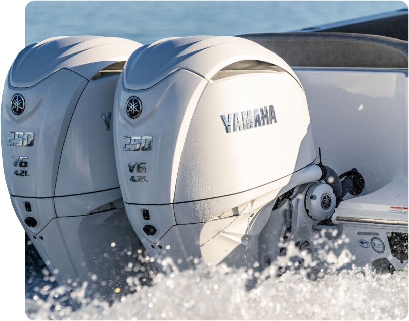 Two white Yamaha 250 V6 outboard engines mounted on the transom of a boat kicking up spray on open water.