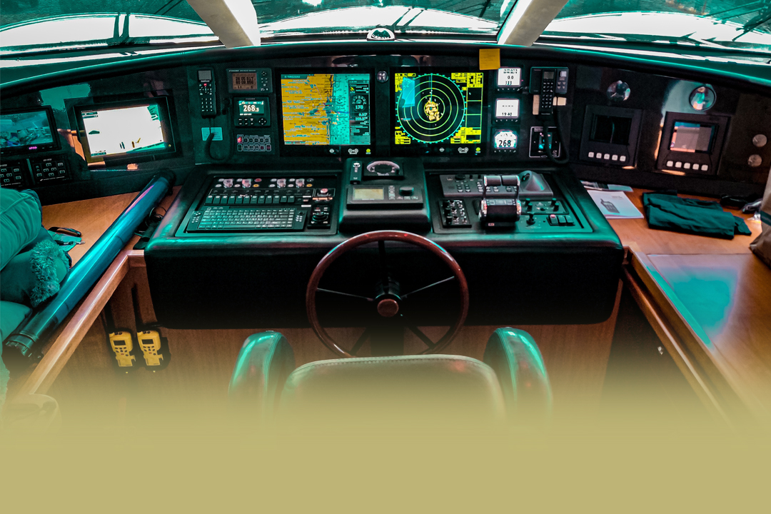 Helm station with steering wheel, chartplotter and radar screens aboard a motor yacht.