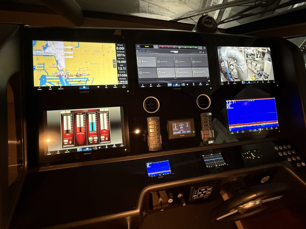 Boat helm station with Garmin chartplotter, engine camera, tank level, and sonar displays installed on the console.