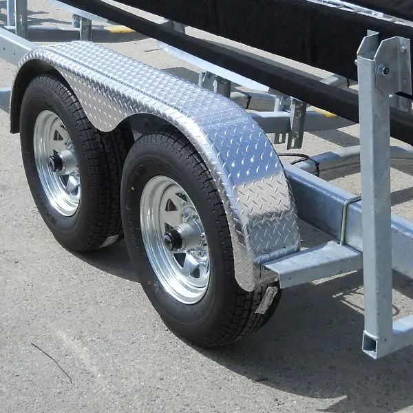 Dual-axle boat trailer with diamond-plate aluminum fenders and galvanized frame supporting a boat hull.