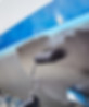 Close-up of a white boat hull with a dark fitting in front of blue water.