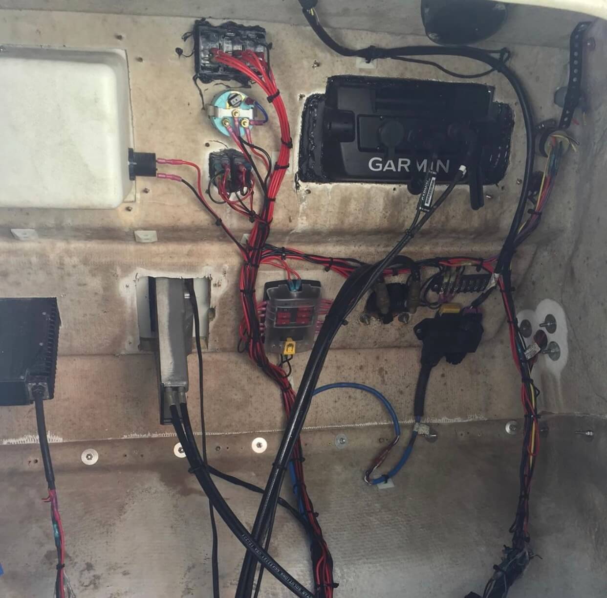 Wiring harness, circuit breakers, fuse block and a Garmin display unit installed in the interior panel of a vehicle being wired.