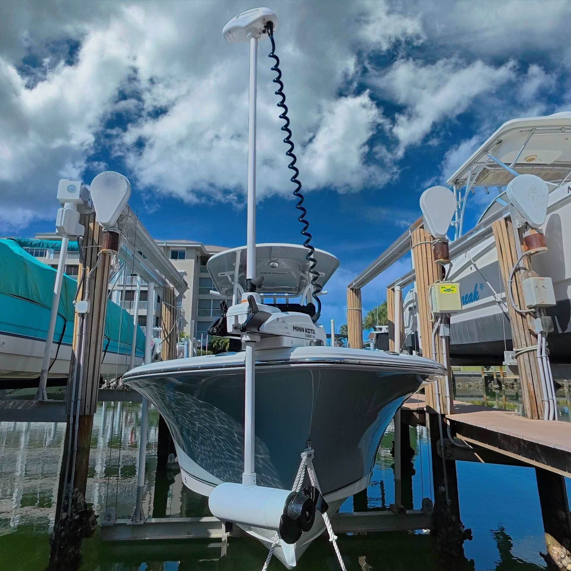 Center console fishing boat with a Minn Kota Terrova trolling motor and GPS unit mounted at the bow, sitting in a boat lift slip at a marina.