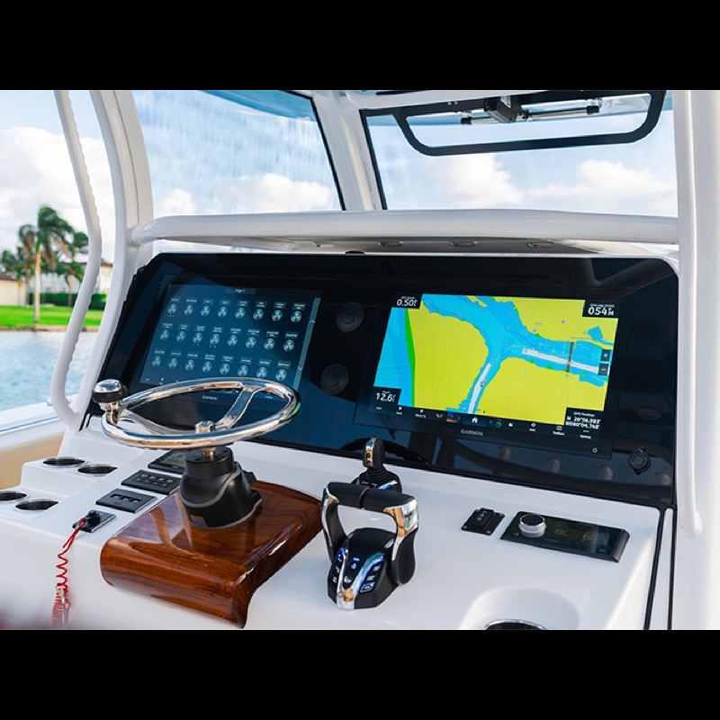 Boat helm with a Garmin chartplotter, engine instrument screens, steering wheel and throttle controls on a white center console boat.