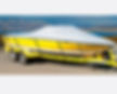 Yellow motorboat with a white canvas cover sitting on a trailer outdoors.