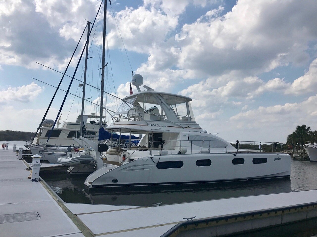 Leopard catamaran power yacht named Cygnus Palace docked at a marina dock under a cloudy sky.