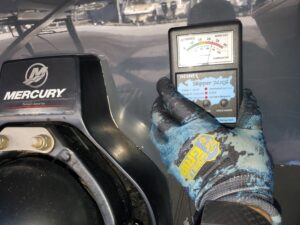 Moisture meter being used on a Mercury outboard motor cowling during a marine inspection.