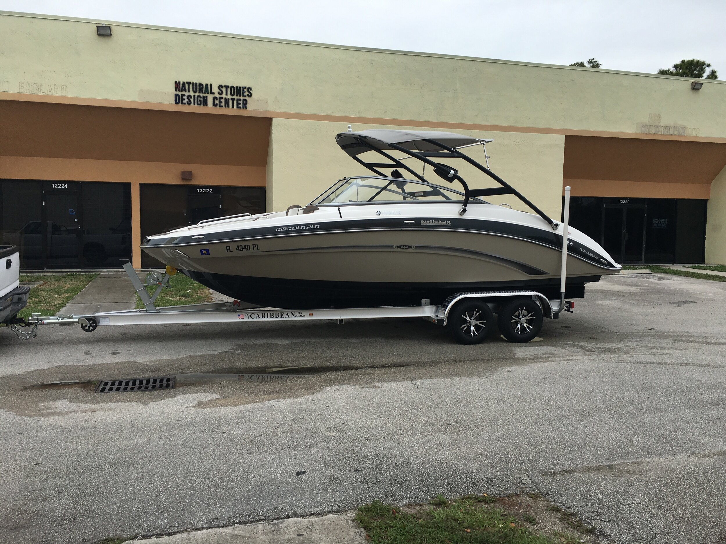 Yamaha 242 Limited sport boat on a Caribbean aluminum trailer parked outside a commercial strip at 12220-12224 block, Florida.