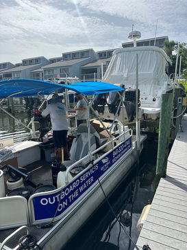 Outboard service boat with a technician working aboard at Outboard Service On The Water, marina dock.