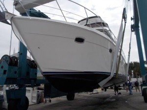 Motor yacht suspended in a travel lift at a boatyard.