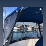 Blue canvas boat enclosure with a marina of moored sailboats behind it.