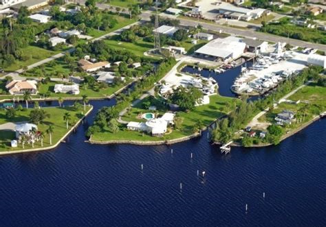 Aerial view of a marina with docked boats and a large storage building along a canal, with waterfront homes nearby.